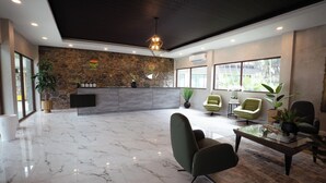 Un moderno vestíbulo de hotel con pared de piedra, un mostrador de recepción y zonas de estar.