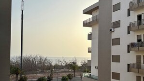 Ein modernes Gebäude mit Balkonen, einer Straßenszene und blauem Himmel.