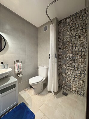Een badkamer met toilet, wastafel en douche.