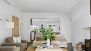 Ein Wohnzimmer mit zwei Sofas, einem Couchtisch, einem Kamin und einer Küche im Hintergrund.