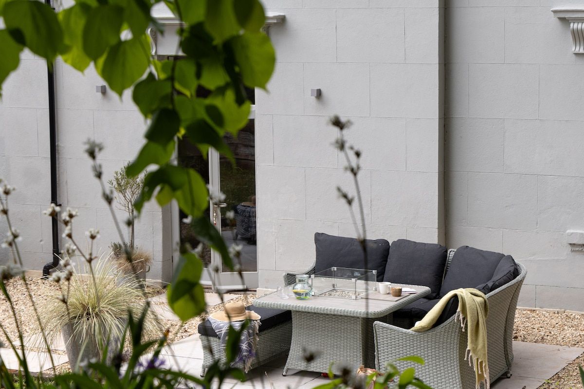 An outdoor seating area with a wicker sofa, a glass-top table, and a potted plant.