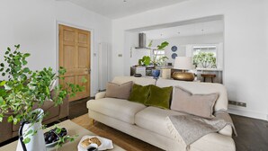 Ein Wohnzimmer mit einer Couch, einem Couchtisch, einer Pflanze und einer Tür.