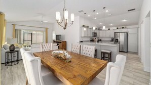 A modern kitchen with white cabinetry, a central island, and stainless steel appliances. - Walk to Brownwood! Spacious 3BR | Golfcart + BBQ (The Villages)