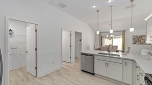 A modern kitchen with white cabinetry, a dishwasher, and pendant lighting. - Walk to Brownwood! Spacious 3BR | Golfcart + BBQ (The Villages)