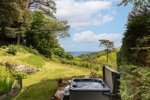 A hot tub in a lush garden with a view of the sea. - Lantern House in Torquay (Torquay)