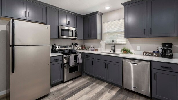 A modern kitchen with grey cabinets, stainless steel appliances, and a white countertop. - Lux Modern Getaway At&t Stadium Views King Bed (Arlington)