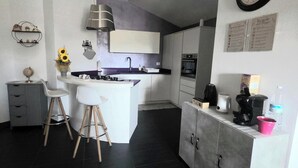 A compact kitchen with a central island, a built-in oven, and a coffee machine. - Apartment in Villa Gra&Mary (Tombaccia)