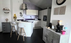 Eine kompakte Küche mit einer zentralen Kochinsel, einem Einbauofen und einer Kaffeemaschine.