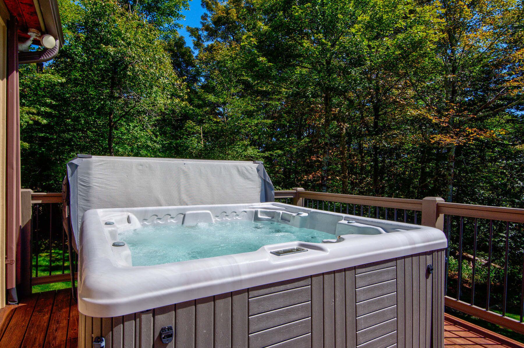 Een hottub op een houten terras, met uitzicht op bomen.