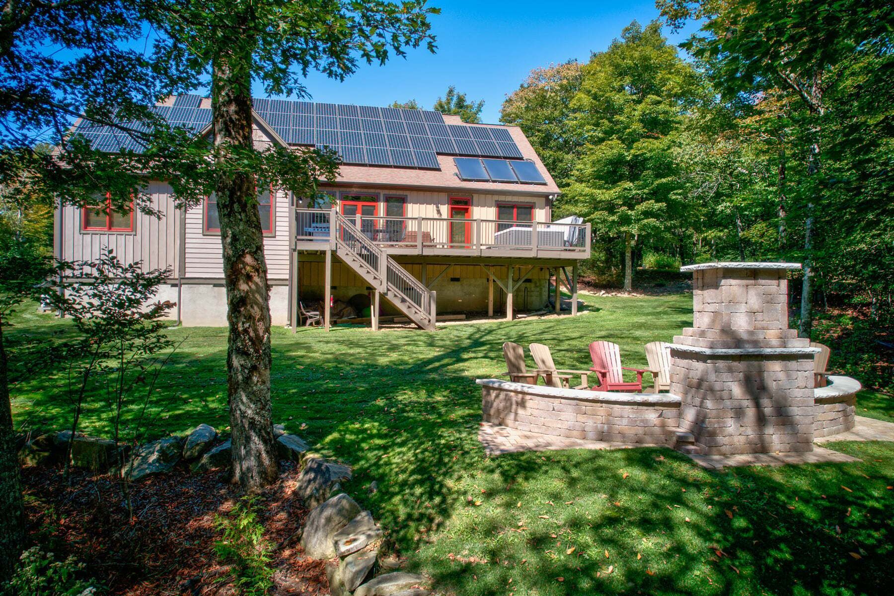 A house with a deck, solar panels, and a stone fire pit.