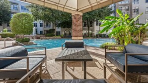 A poolside area with lounge chairs, a table, and a canopy. - Relaxing 1BR Modern Home Getaway Perfect w/ Pool (Irving)
