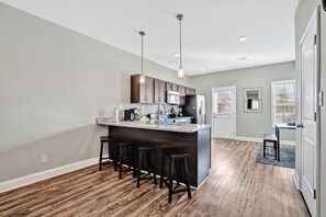 A modern kitchen with a central island, bar stools, and pendant lighting. - Legacy Executive Retreat (Clarksville)