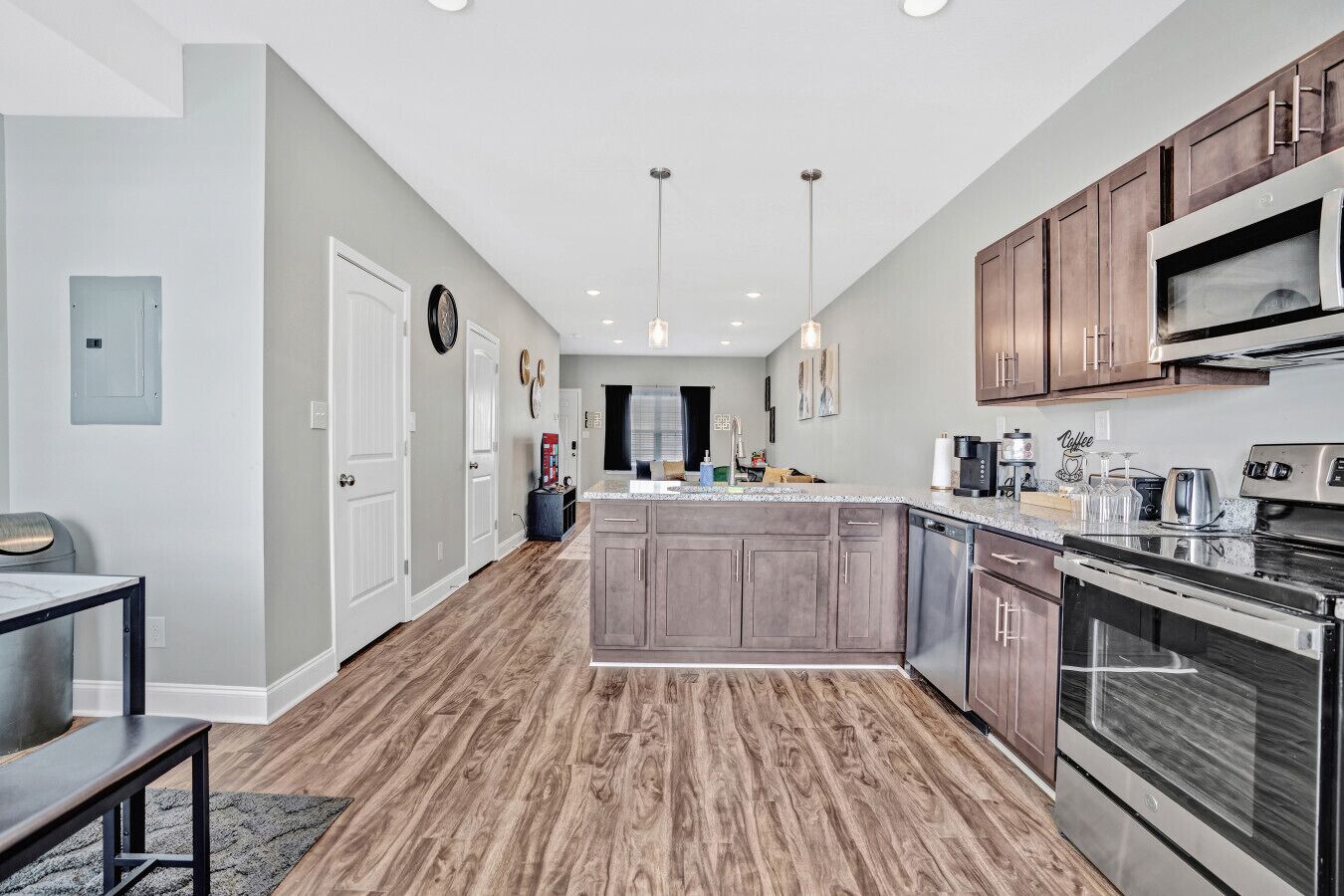 A modern kitchen with wooden flooring, stainless steel appliances, and a central island.