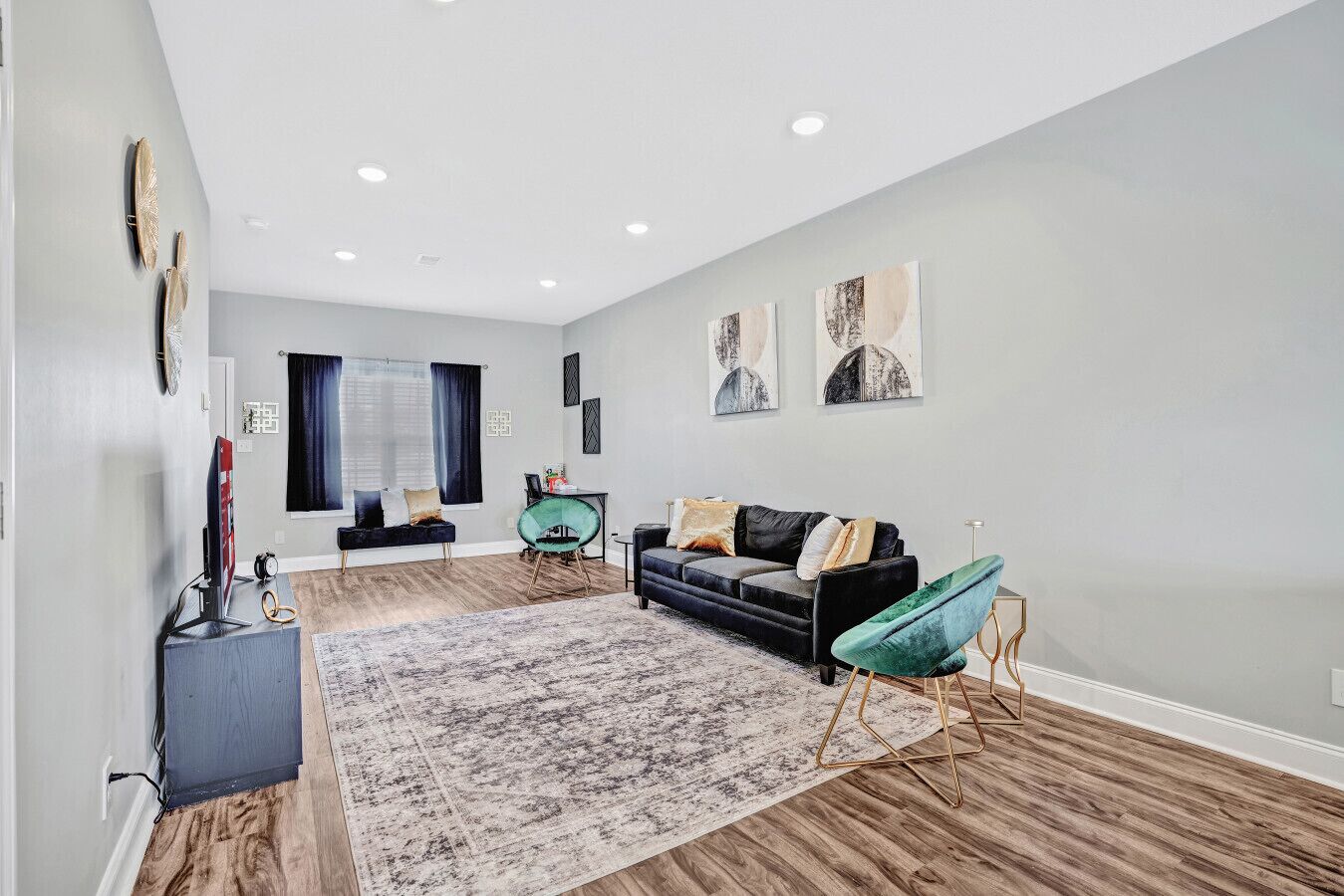 Una sala de estar moderna con un sofá oscuro, un sillón verde y una alfombra grande.