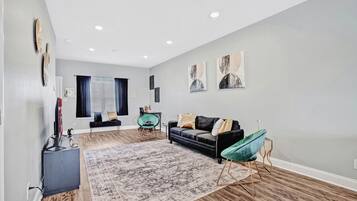 Una sala de estar moderna con un sofá oscuro, un sillón verde y una alfombra grande.
