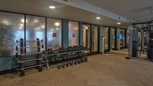 Une salle de sport équipée de matériel de musculation, d’un miroir et d’un sol à motifs en chevrons.