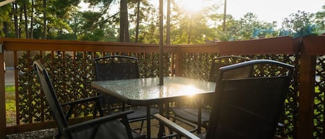A patio with a table and chairs, surrounded by a wooden fence and trees.
