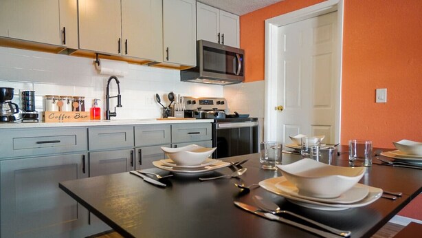 A modern kitchen with white cabinets, a microwave, and a coffee bar. - King Suite, 10 Mins to Ft Moore (Columbus)