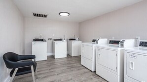 A laundry room with four washing machines and a chair. - King Suite, 10 Mins to Ft Moore (Columbus)