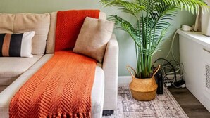 Una sala de estar con un sofá, una planta grande en maceta y un mapa en la pared.