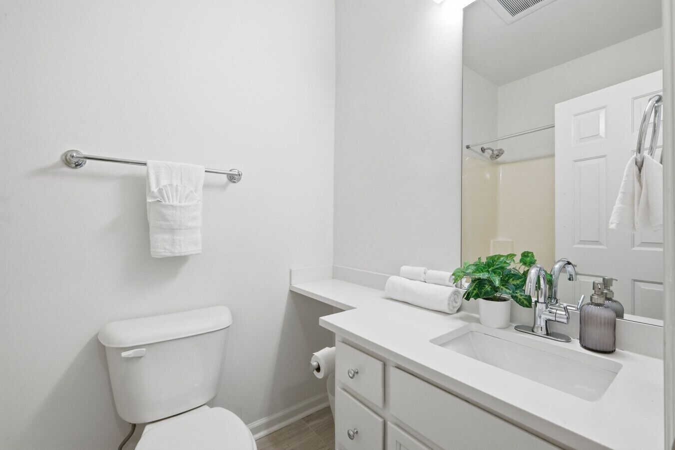 Un baño moderno con inodoro, lavamanos, espejo y barra para toallas.