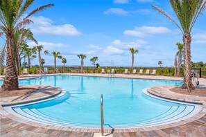 A swimming pool with palm trees, lounge chairs, and a clear blue sky. - Salty Dog | Fence • Golf Cart • Beach Access (Port Saint Joe)