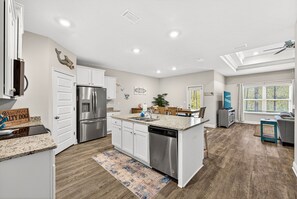 A modern kitchen with white cabinets, stainless steel appliances, and a central island. - Salty Dog | Fence • Golf Cart • Beach Access (Port Saint Joe)