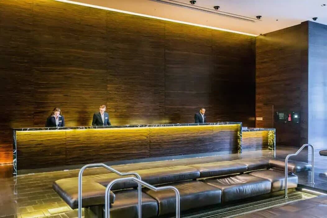 A reception area with a long counter, three staff members, and a seating area with metal railings.
