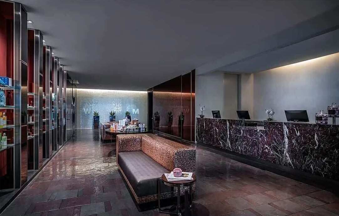 Un lobby moderno con una mesa de recepción, zona de estar y vitrinas de vidrio.