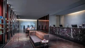 Un lobby moderno con una mesa de recepción, zona de estar y vitrinas de vidrio.