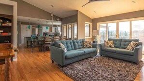 A spacious living room with a large sofa set, a dining area, and a kitchen in the background. - 550 Massive 4 Bedroom Home Sleeps 19 (Candler)