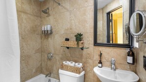 A bathroom with a bathtub, toilet, and sink. There are toiletries on the wall and a mirror above the sink. - Centrally Located APT in NYC Walk to Time Square (New York)