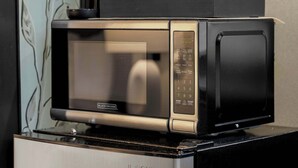 A compact microwave on a black appliance, possibly a coffee maker, with a small stack of white cups and a red item on top. - Centrally Located APT in NYC Walk to Time Square (New York)