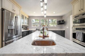 A modern kitchen with a large island, stainless steel appliances, and a TV mounted above the counter. - 561b Massive 3 Bedroom With Large Backyard (Orlando)