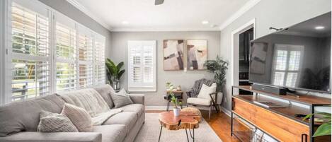 A living room with a sofa, coffee table, TV stand, and artwork on the wall.