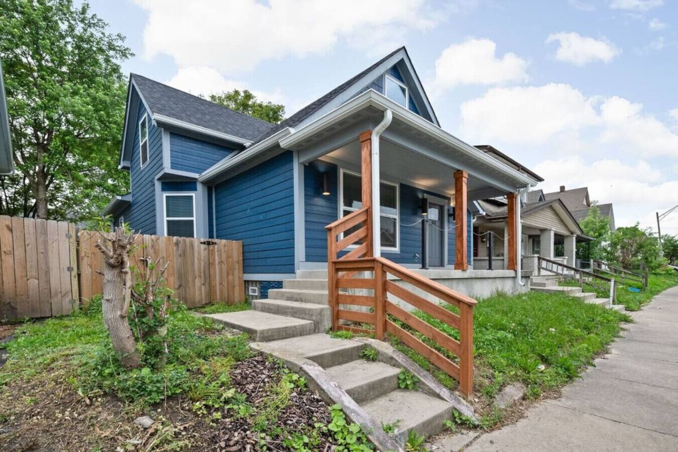 A two-story house with a front porch and a wooden staircase leading to the entrance.