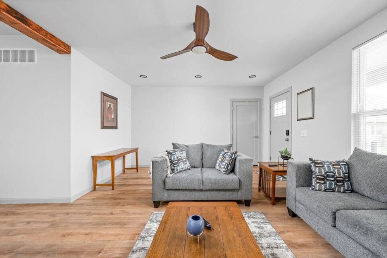 A modern living room with a grey sofa, a wooden coffee table, and a ceiling fan.