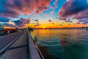 A sunset over a body of water with a road and a tanker truck on the left. - 593 Secluded Villa 3 Bedrooms Heated Pool (North Bay Village)