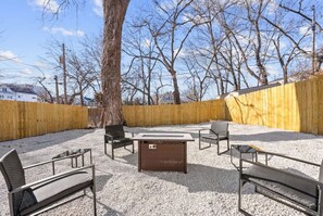 An outdoor patio with a fire pit, seating, and a wooden fence. - 564 Massive 5 Bedroom With hot tub Close to Plaza (Kansas City)