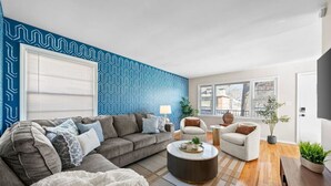 Een moderne woonkamer met een hoekbank, twee fauteuils, een salontafel en een behang met een patroon.