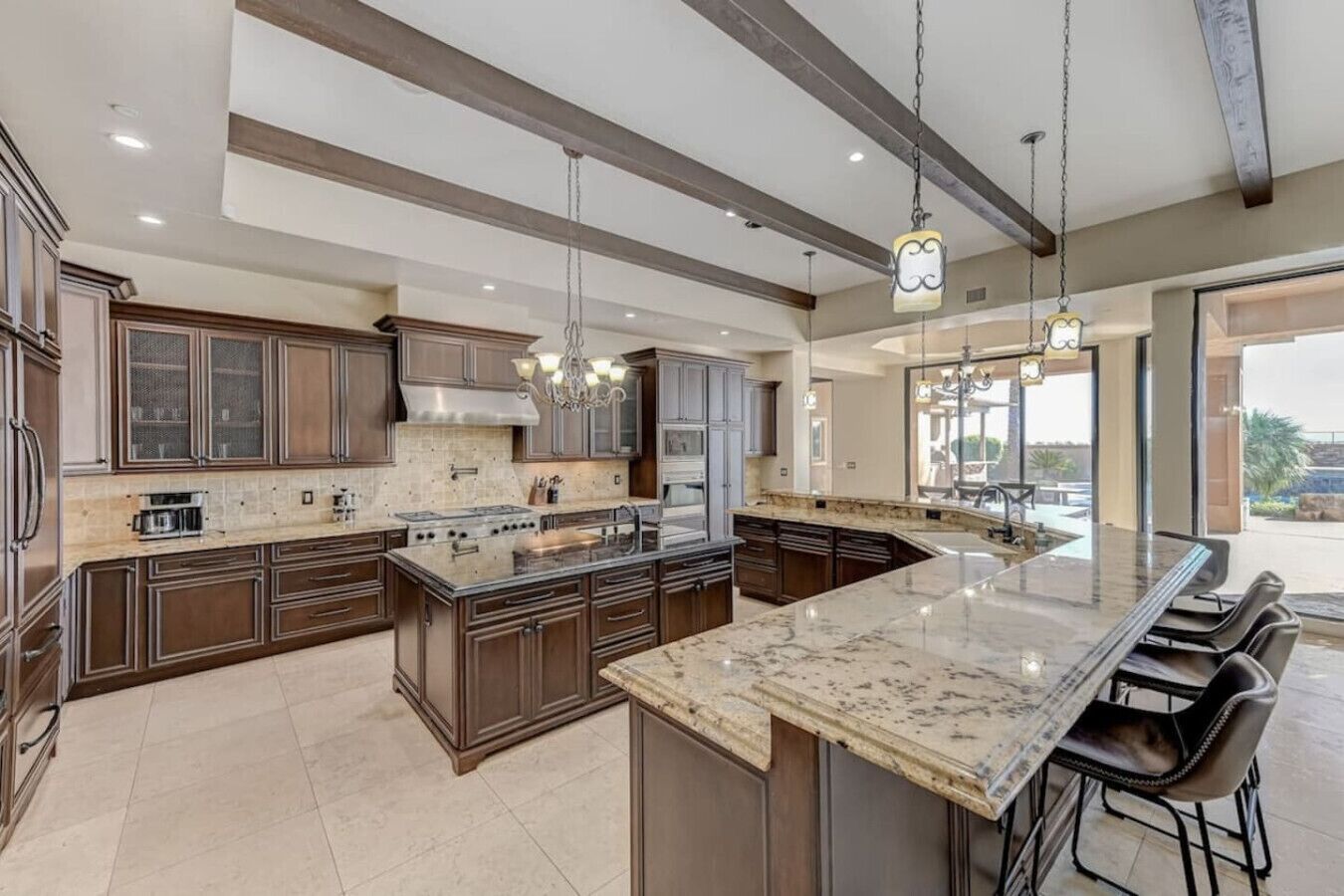 A spacious kitchen with a large island, dark wood cabinets, and a modern chandelier.