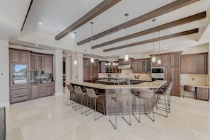 A modern kitchen with a large island, bar stools, and pendant lighting. - 591d Theater Room 11 Beds - Spa (Las Vegas)