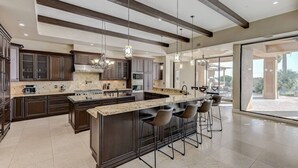 A spacious kitchen with dark wood cabinets, a large island with bar stools, and pendant lighting. - 591d Theater Room 11 Beds - Spa (Las Vegas)