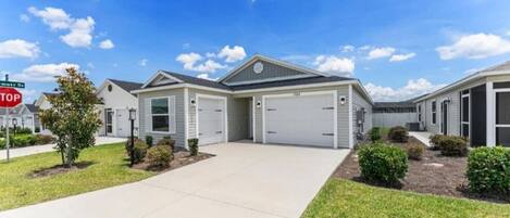 A residential building with a garage, a driveway, and a well-maintained lawn.
