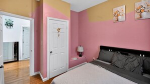 A bedroom with a bed, bedside table, lamp, and two paintings on the wall. - 607 Massive 5 Bedroom Close to NYC (Newark)