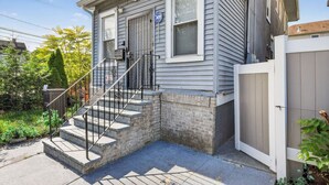 A two-story house with a front porch, a staircase, and a fenced yard. - 607 Massive 5 Bedroom Close to NYC (Newark)
