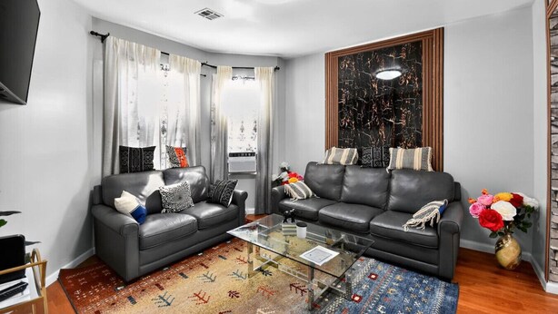 A modern living room with two grey sofas, a glass coffee table, and a patterned rug. - 607 Massive 5 Bedroom Close to NYC (Newark)