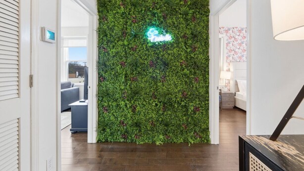 Un pasillo con pared de jardín vertical verde y un letrero de neón.