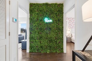A hallway with a green vertical garden wall and a neon sign. - Bright 3BR Aptclose to Universities Parking (Nashville)