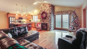 A spacious living room with a fireplace, a dining area, and a kitchen with wooden cabinets and a stone accent wall. - 519c On the Lake Hot Tub Pool Table 10 Beds (Howard Lake)